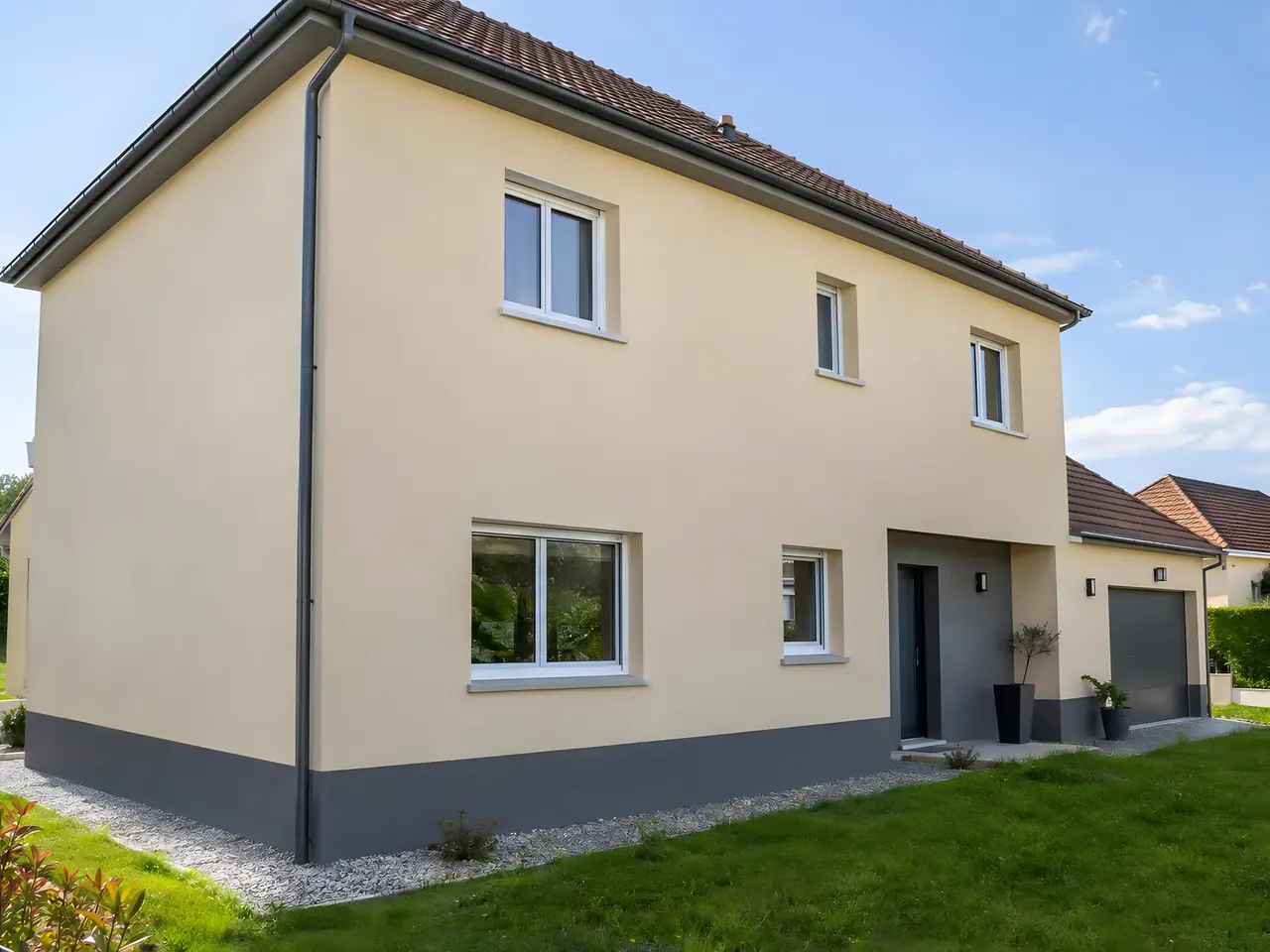 Maison à étage à l'enduit beige neuf, soubassement gris anthracite et allée de gravier