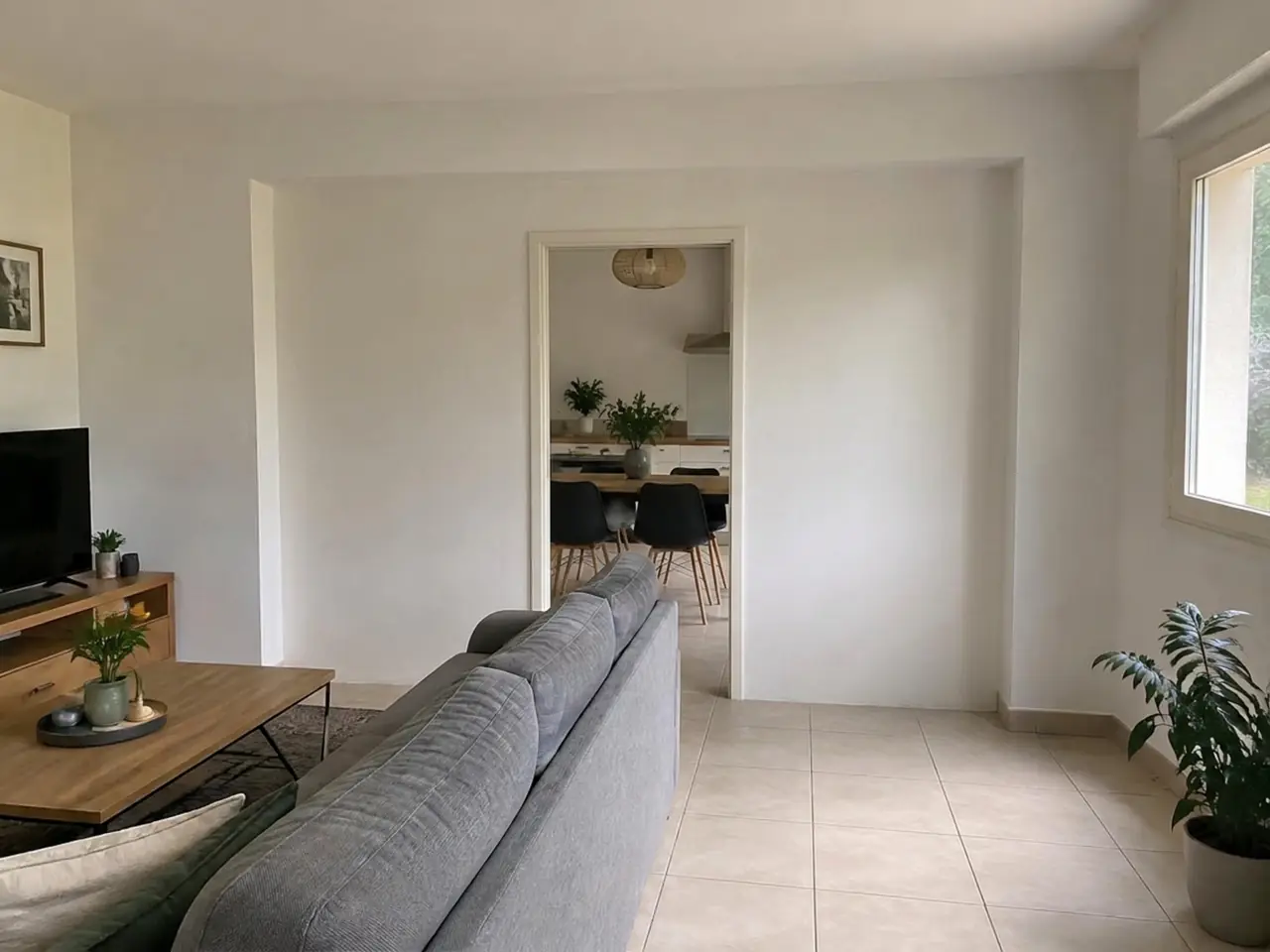 Mur blanc entre séjour et cuisine percé d'une simple porte, canapé gris devant, avant son ouverture